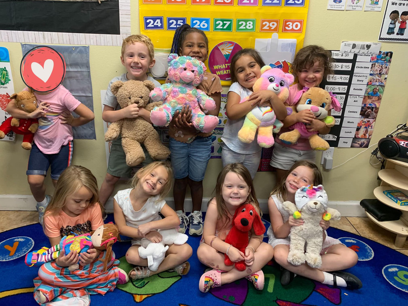 a group of children holding stuffed animals in a classroom