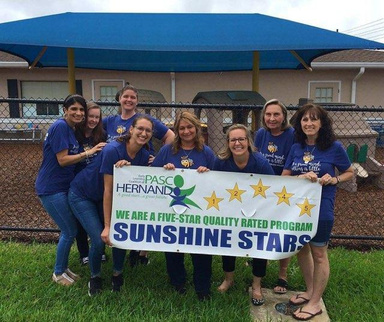 a group of day care staff holding a banner that says sunshine stars