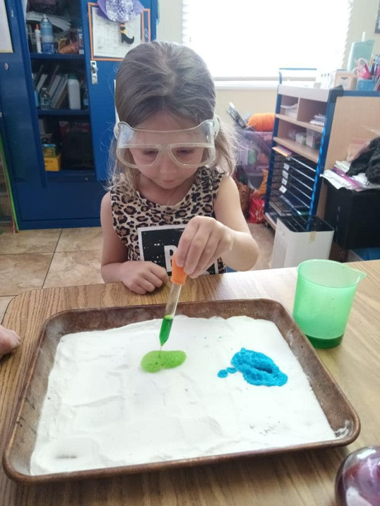 Young girl using pipette for a fun experiment in class